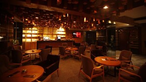 Um espaço de bar com pouca luz, móveis de madeira e uma tela de televisão.