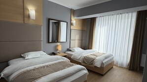 Quarto de hotel com duas camas, um espelho grande, mesa de cabeceira com abajur e luz no teto.