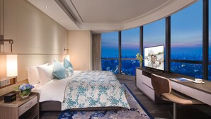 Habitación de hotel moderna con una cama grande, un escritorio y vistas a la ciudad.