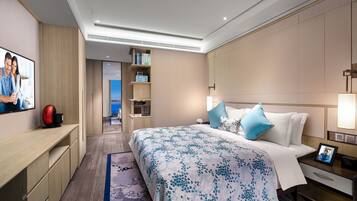 Ein modernes Hotelzimmer mit einem großen Bett, einem Fernseher, einem Schreibtisch und einem Bücherregal.