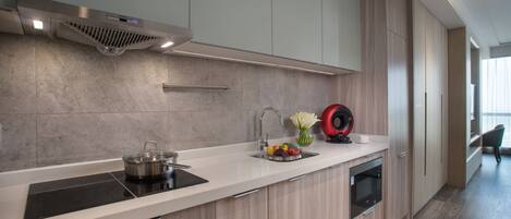 Una cocina moderna con campana extractora de acero inoxidable, horno empotrado y un lavamanos con un jarrón de flores.