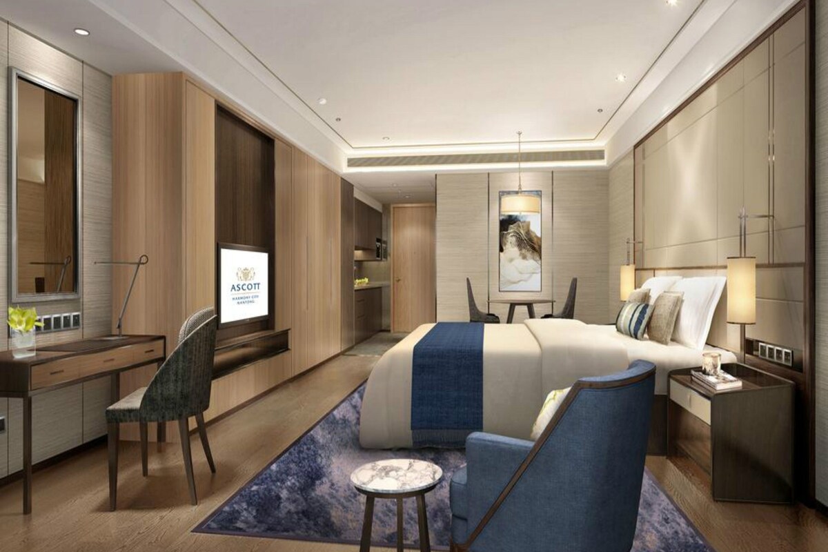 Una habitación de hotel moderna con cama, escritorio, silla y una mesita.