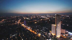 Un hôtel de grande hauteur au design moderne, entouré d’un paysage urbain au crépuscule.