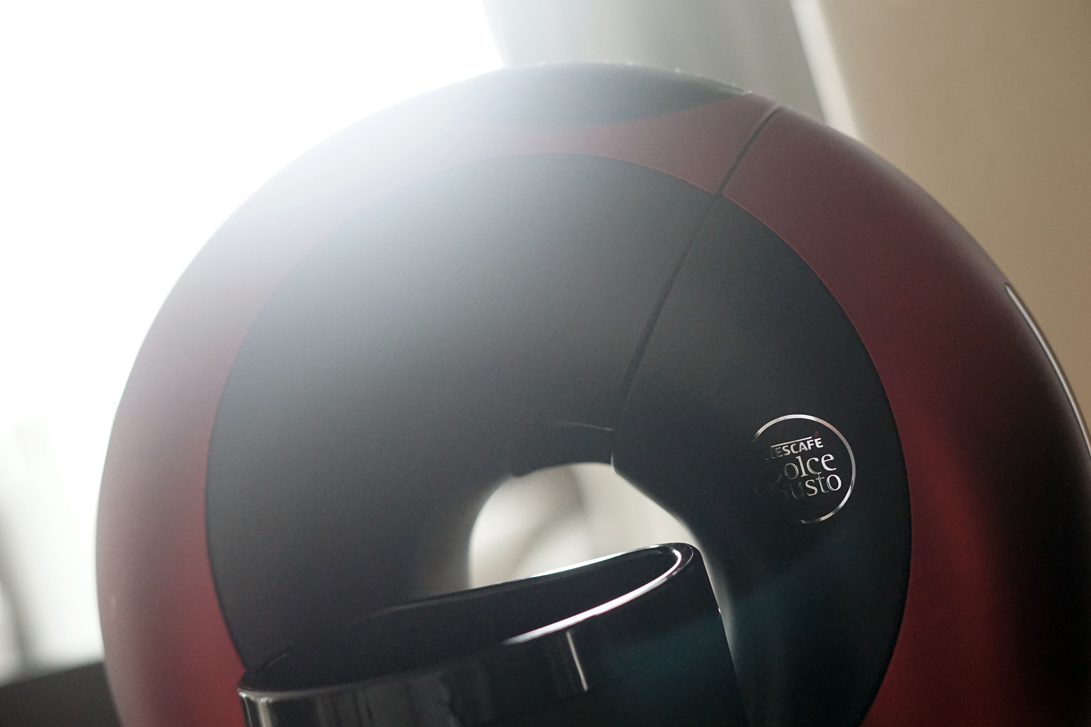 A close-up of a red and black espresso machine with a visible brand logo.