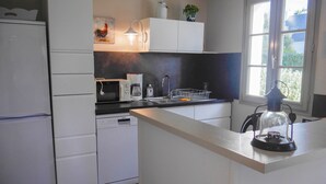 Una cocina moderna con armarios blancos, microondas, cafetera y pileta.