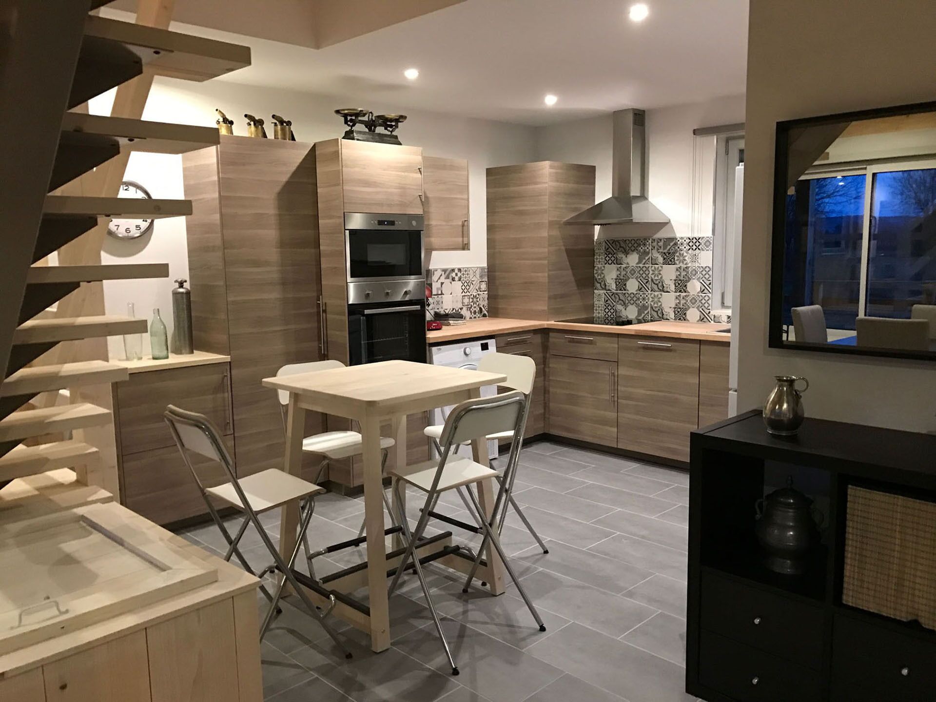 Une cuisine moderne dotée d’un îlot central, d’un four encastré et d’une grande fenêtre.