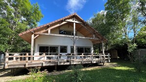 Une cabane en bois dotée d’un porche, de grandes fenêtres et d’une terrasse couverte.