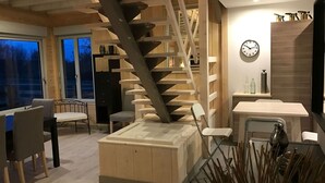 Un intérieur moderne avec un escalier en bois, un coin repas et une cuisine équipée d’un évier et de placards.