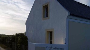 Un bâtiment blanc avec une porte de garage et une petite fenêtre, portant l’inscription « Cadiennes ».