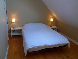 A bedroom with a white bed, two bedside tables with lamps, and wooden flooring. - Semi-detached house with garden, 4 beds, peaceful in Locmaria (Locmaria)