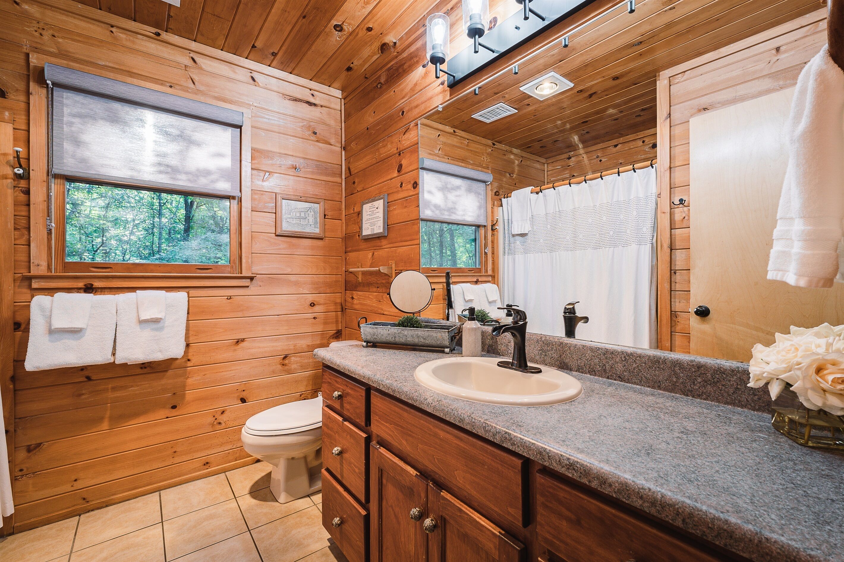 A wooden cabin bathroom with a sink, mirror, and toilet.