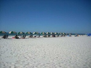Een strand met rijen strandparasols en ligstoelen.
