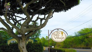 A large tree with a sign for "The Sea Village" restaurant. - Direct oceanfront condo with A/C @ Sea Village (Kailua-Kona)