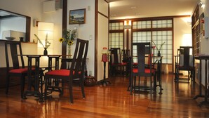 A traditional Japanese-style dining room with wooden flooring, red cushioned chairs, and a table. - La Passione Boutique B&B (Naha)