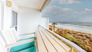 Een balkon met uitzicht op strand en zee.