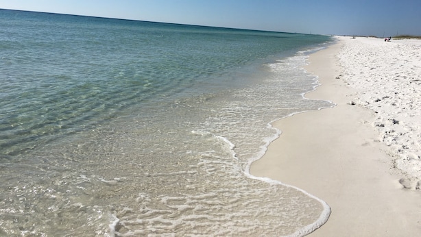 Een strand met helder ondiep water en een zandstrand.