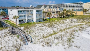 Een strandhotel met meerdere verdiepingen, terras en een zandstrand.