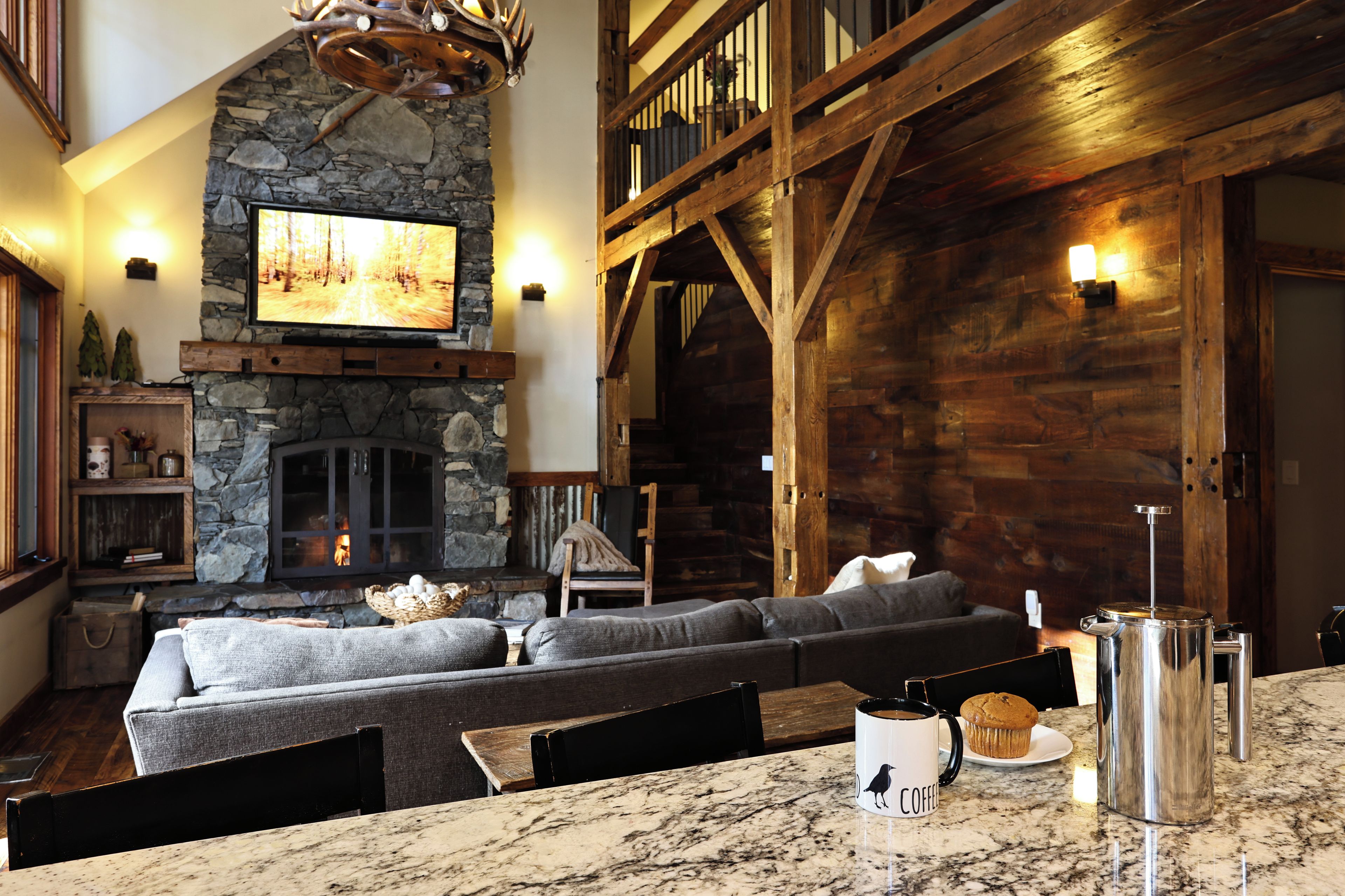A cozy living room with a stone fireplace, a large television, and a comfortable seating area.