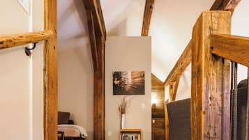 Un escalier en bois mène à une chambre à coucher qui contient un lit et une bibliothèque.