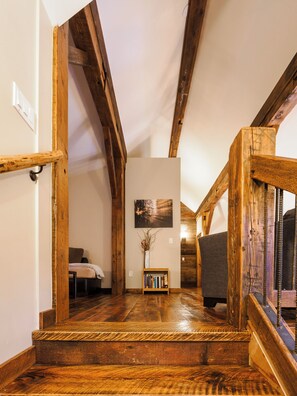 Eine Holztreppe führt zu einem Schlafzimmer mit einem Bett und einem Bücherregal.