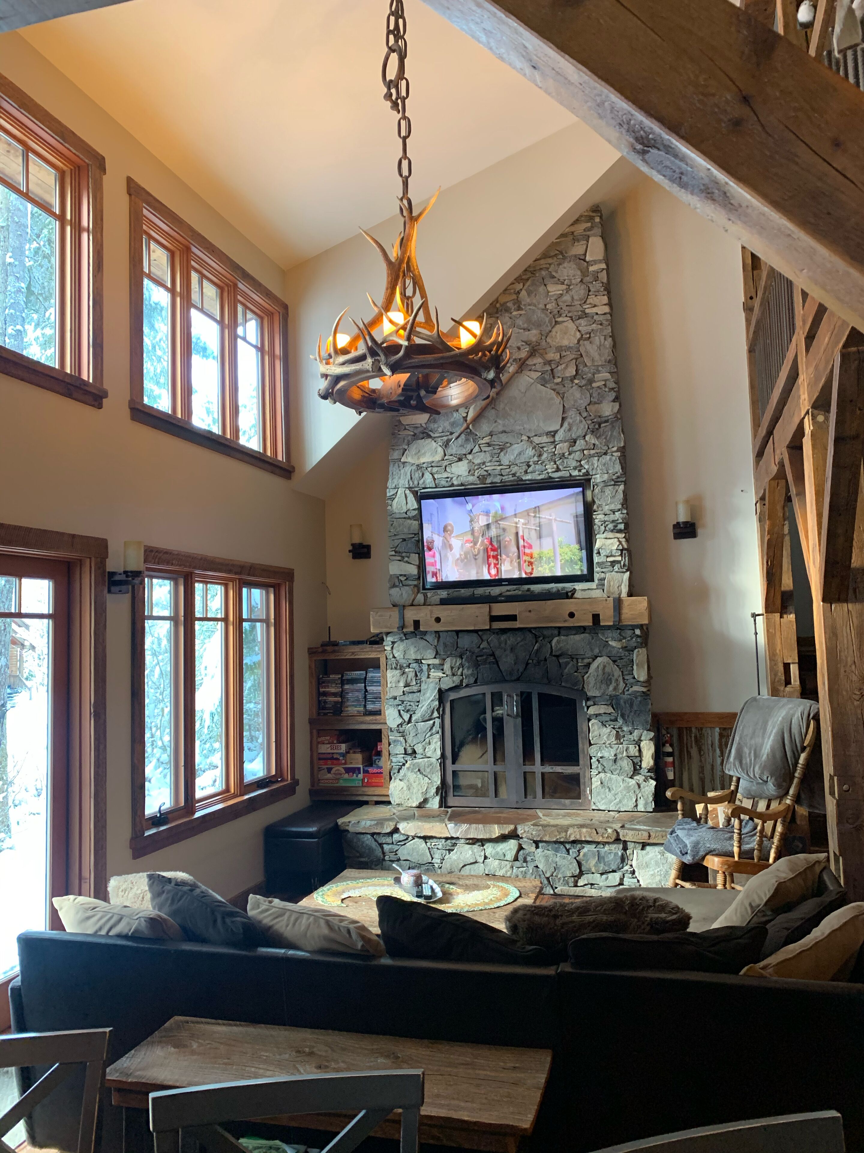 Una sala de estar acogedora con chimenea de piedra, un televisor montado encima y una zona de estar confortable con un sofá y un sillón.