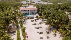 Un resort con piscina, rodeado de palmeras y una playa.