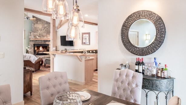A dining area with a wooden table, cushioned chairs, and a decorative glass vase. - Outpost: Moose Creek 20 - Private Hot Tub! (Teton Village)