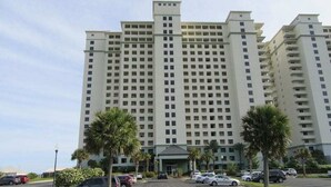 A large, multi-story hotel with a central entrance, parking lot, and palm trees. - Corner Unit A1110 Kng/Qn/Bunk/Sofa Sleeper Direct Gulf View-WIFI - Sleeps 9 (Gulf Shores)