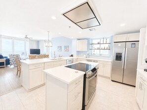 A modern kitchen with a central island, stainless steel appliances, and a dining area with a view. - Corner Unit A1110 Kng/Qn/Bunk/Sofa Sleeper Direct Gulf View-WIFI - Sleeps 9 (Gulf Shores)