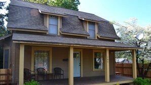 A two-story house with a porch, a front door, and two windows.