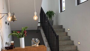 Un escalier avec une rampe noire, une console en bois ornée d’objets décoratifs et une plante en pot.