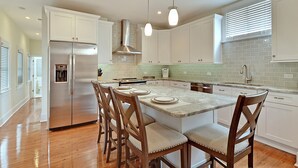 A modern kitchen with white cabinetry, a stainless steel refrigerator, wooden chairs, and pendant lighting. - AWESOME PROPERTY, GREAT DOWNTOWN CHARLESTON LOCATION! Sleeps 10 (Charleston)