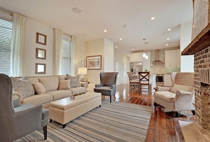 A spacious living room with a sofa, armchairs, and a dining area with chairs and a table.