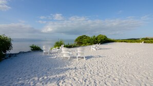 En strand med vita stolar och fri utsikt över havet.