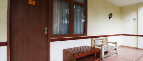 A wooden bench and a door with a number sign.