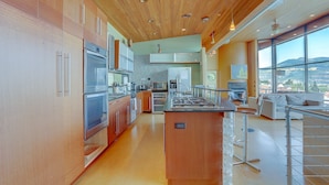 A modern kitchen with wooden cabinets, stainless steel appliances, and a large island. - Alizes - Luxury, Flagship Best Gorge Views, Downtown, Theater Room, Exceptional (Hood River)