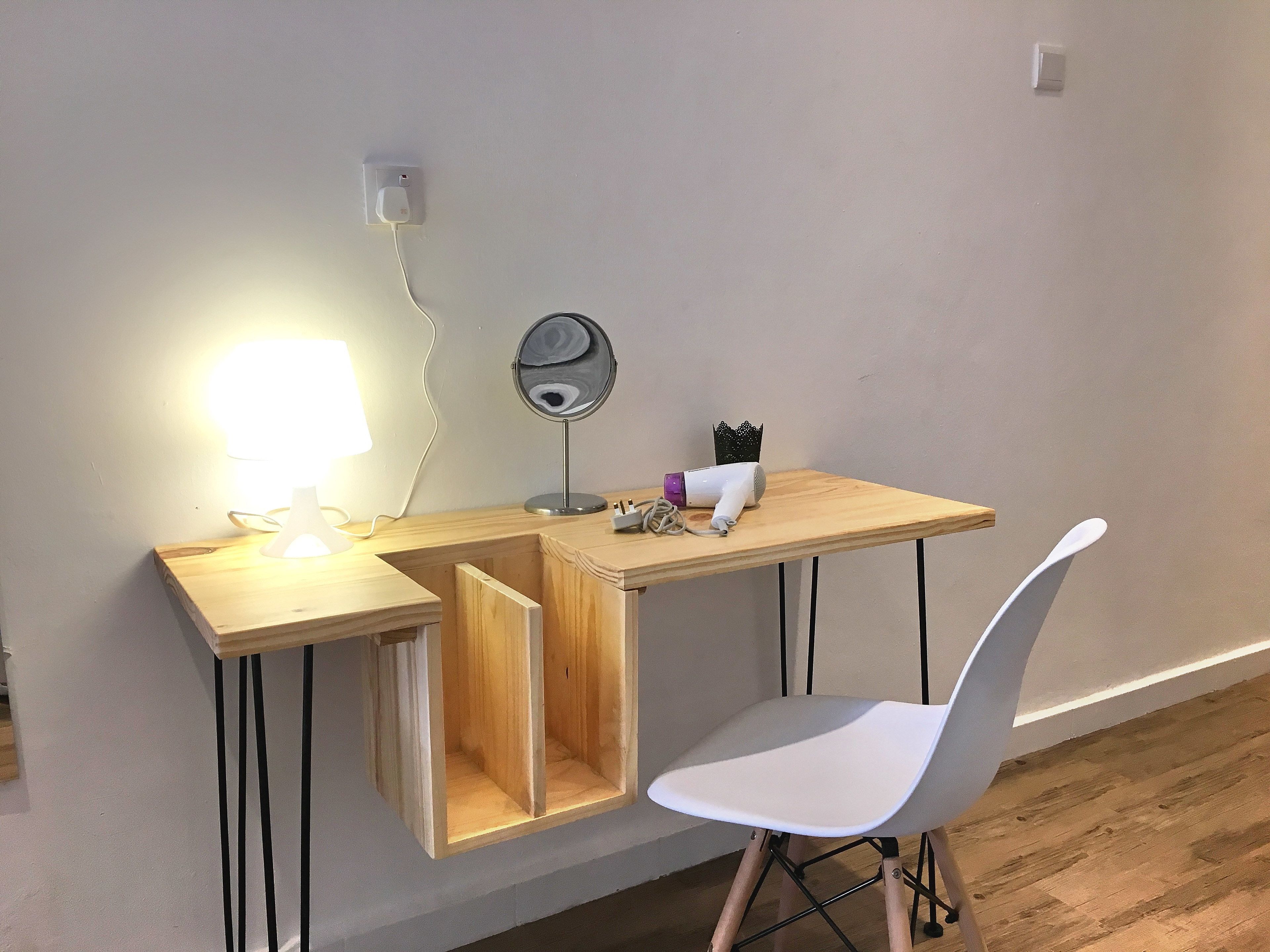 A compact workspace with a desk, chair, lamp, and a small mirror.