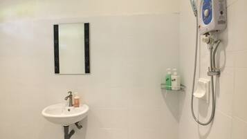 Ein Badezimmer mit weißem Waschbecken, einem Spiegel und einer Dusche inklusive Handbrause.