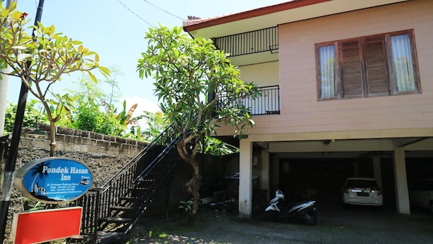 A two-story building with a staircase leading to a balcony. There is a sign for 'Pondok Hasan Inn' and a parked motorcycle. - Pondok Hasan (Nusa Dua)