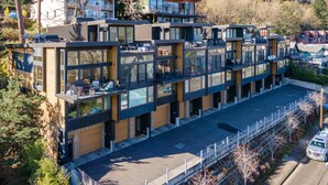 Un edificio moderno de varios pisos con amplios ventanales, balcones y un estacionamiento.