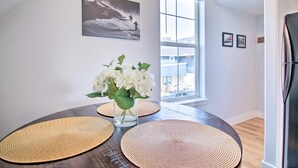 A dining area with a round table, two placemats, a vase with white flowers, and a painting on the wall. - Coldsmoke Getaway, Steps From Meyers Lake & minutes from downtown! (Bozeman)