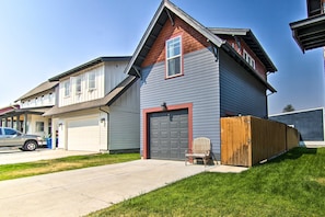 A two-story house with a garage, a driveway, and a wooden fence.