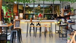 A cafe with a rustic interior, featuring exposed brick walls, wooden tables, and hanging plants. - Room 9 Hometel (Pathio)
