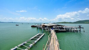 A wooden pier extending into calm water, with boats docked nearby and a small building at the end. - Room 9 Hometel (Pathio)