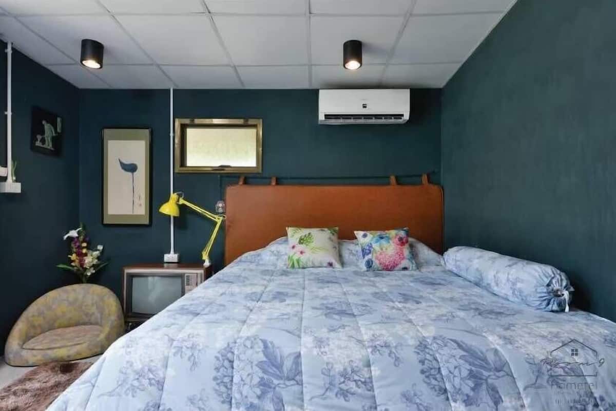 Un dormitorio con cama, mesita de noche, televisor y aire acondicionado.