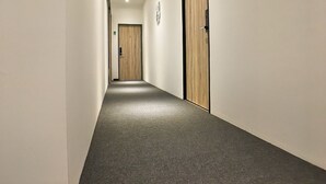 A narrow hallway with carpeted floors and wooden doors on both sides. - iBook6 Deluxe Family Suite for 4 by iBook Homestay (George Town)