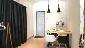 A modern dining area with a table set for four, a black and white chair arrangement, and a black curtain on the left. - iBook6 Deluxe Family Suite for 4 by iBook Homestay (George Town)