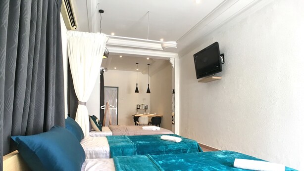 A hotel room with two beds, a TV mounted on the wall, and a bathroom visible through an open door. - iBook6 Deluxe Family Suite for 4 by iBook Homestay (George Town)