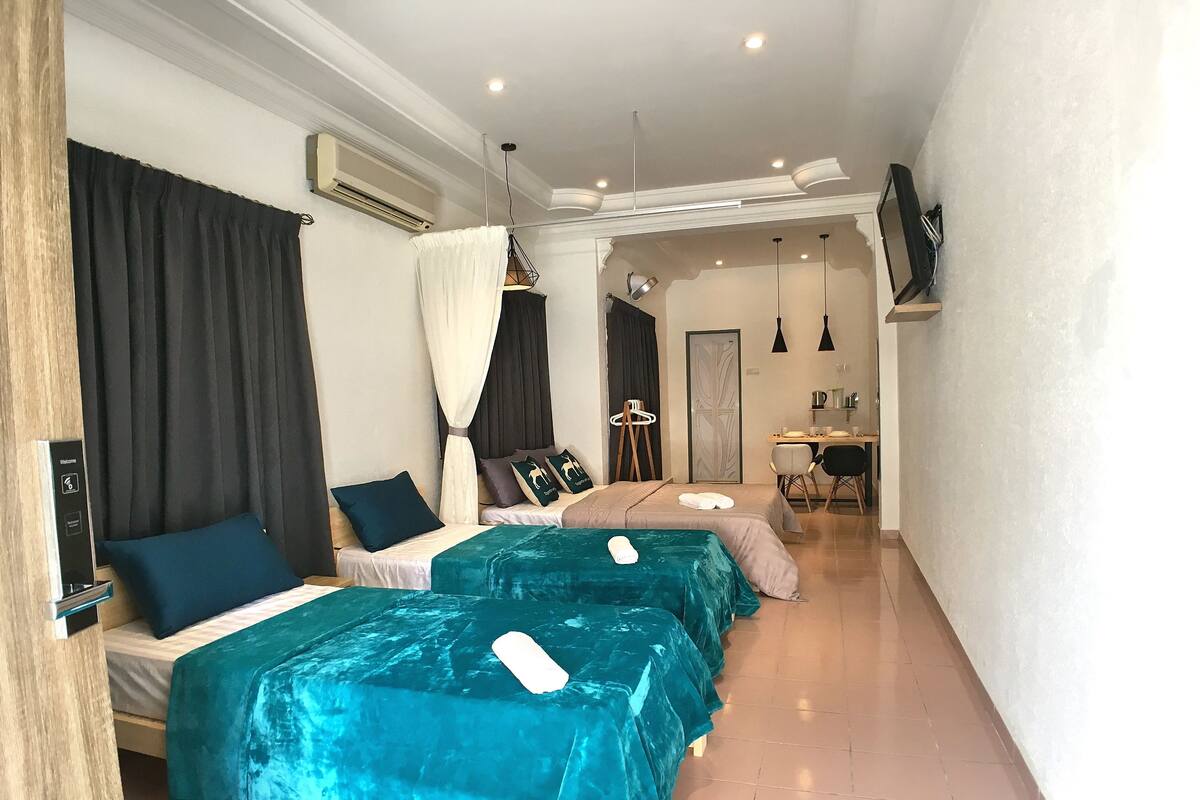 A hotel room with two beds, a desk, a chair, and a TV.