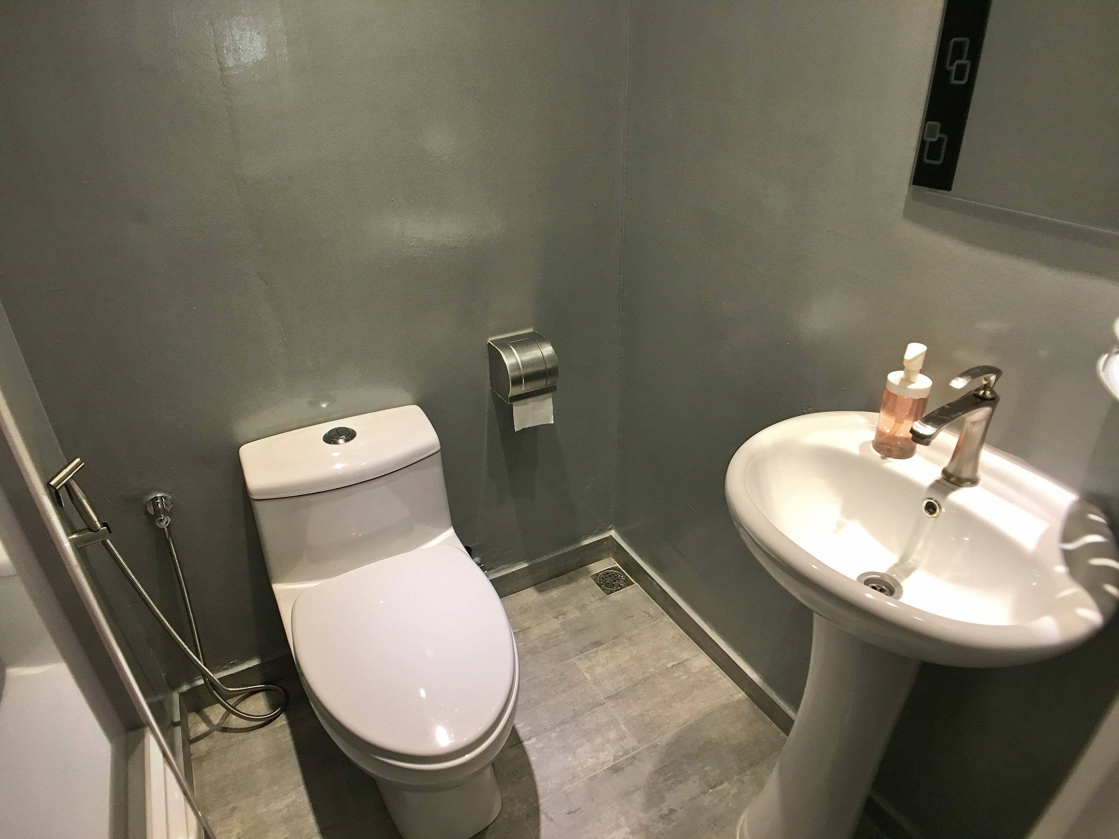 A small bathroom with a toilet, a sink, and a hand dryer.